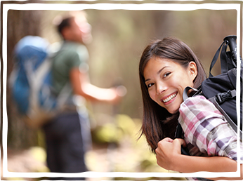 young woman wearing backpack hiking smiling